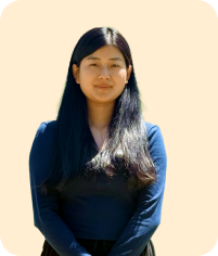 Woman with long black hair wearing black top looking forward on light peach background